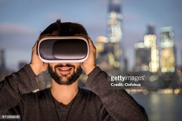 jeune homme semble fasciné dans le casque de réalité virtuelle - flying goggles stock photos et images de collection