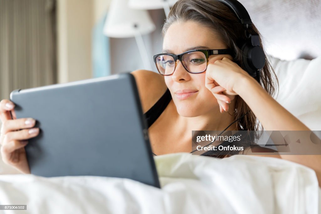 Hermosa mujer joven con tableta Digital en la cama