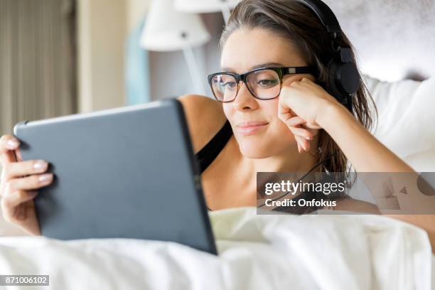 beautiful young woman using digital tablet in bed - sleepless 2017 film stock pictures, royalty-free photos & images