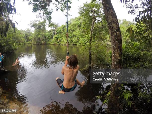 family enjoys a guided exploration of the amazon jungle on a remote part of the river. - rope swing stock pictures, royalty-free photos & images