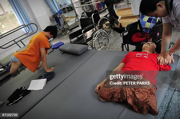 Nurse massages Huang Li as 19-year-old double amputee Dai Guohong does press-ups in the Hong Kong-funded Stand Tall earthquake rehabilitation centre...