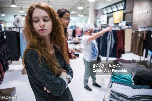 the silver-haired 65-years-old active senior woman and her two teenager granddaughters, sisters, shopping in the clothing retail store - 14 15 years girl stock pictures, royalty-free photos & images