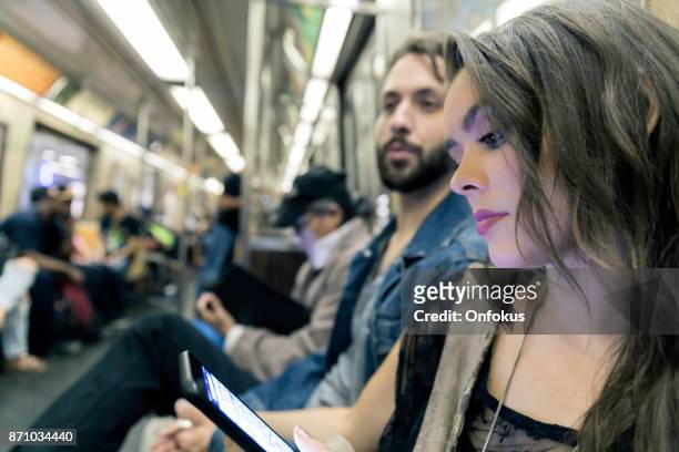 young woman using phone in subway train, new york city - looking at subway map stock pictures, royalty-free photos & images