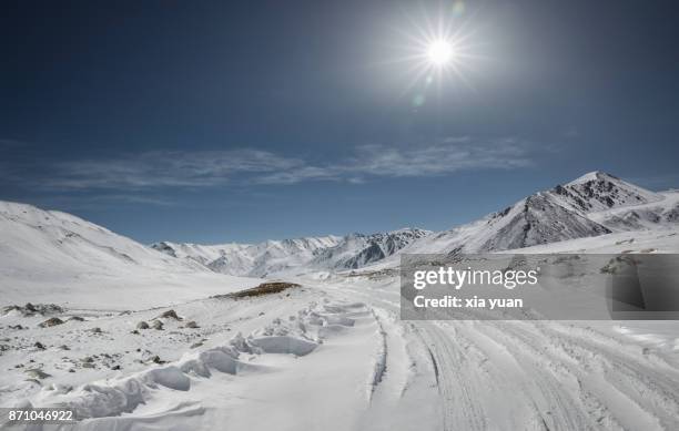 snowy road in mountains against sunlight - snowcapped mountain stock pictures, royalty-free photos & images