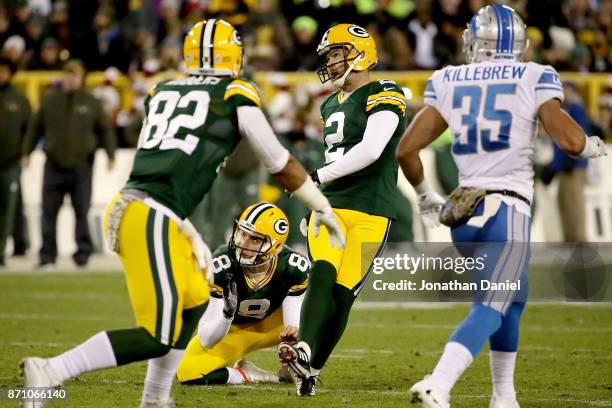 Mason Crosby of the Green Bay Packers kicks a field goal as Justin Vogel holds in the second quarter against the Detroit Lions at Lambeau Field on...