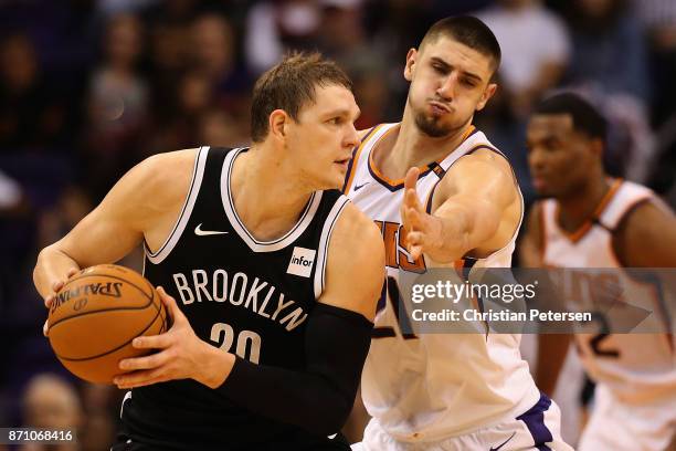 Timofey Mozgov of the Brooklyn Nets looks to pass under pressure from Alex Len of the Phoenix Suns during the first half of the NBA game at Talking...