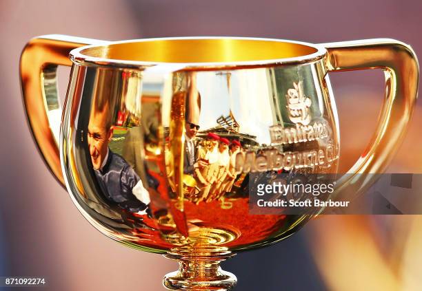 Jockey Corey Brown and trainer Joseph O'Brien are reflected in the Melbourne Cup trophy after Rekindling ridden by jockey Corey Brown won race 7 the...