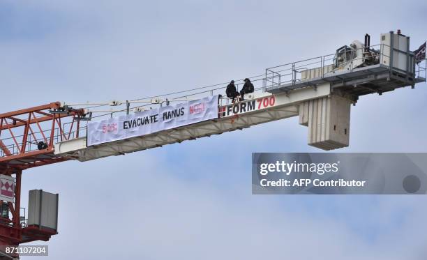 Demonstrators hang a banner concerning the plight of refugees on Papua New guinea's Manus Island on a nearby construction crane ahead of the running...