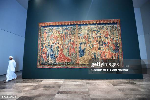 Man walks past the medieval "Tapestry of Daniel and Nebuchadnezzar" displayed at the Louvre Abu Dhabi Museum during a media tour on November 6 prior...