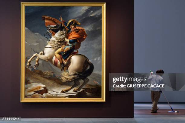 Cleaner mops the floor near to the 1803 painting "Napoleon Crossing the Alps" by French artist Jacques-Louis David, on display at the Louvre Abu...