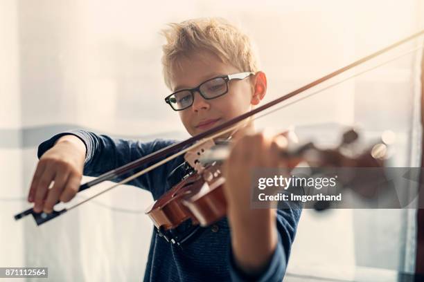 pequeño violín practicante de niño - kids instruments fotografías e imágenes de stock