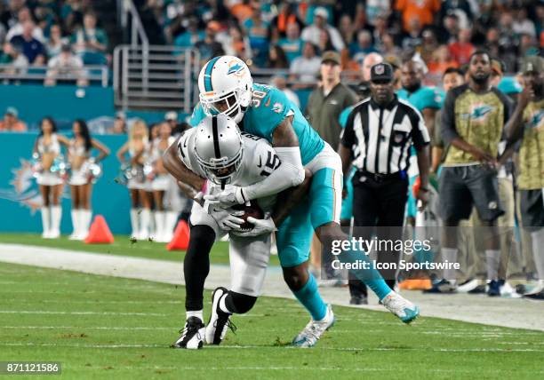 Miami Dolphins corner back Cordrea Tankersley tackles Oakland Raiders wide receiver Michael Crabtree during an NFL football game between the Oakland...