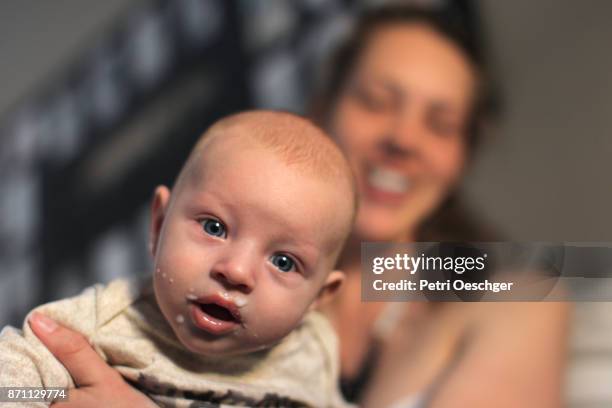 a young mother burping her baby boy after breastfeeding. - muttermilch stock-fotos und bilder