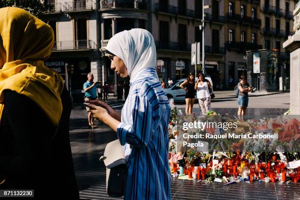 Two young muslim women along with tourists and locals gather at a memorial tribute of flowers, messages and candles to the victims of the terrorist...