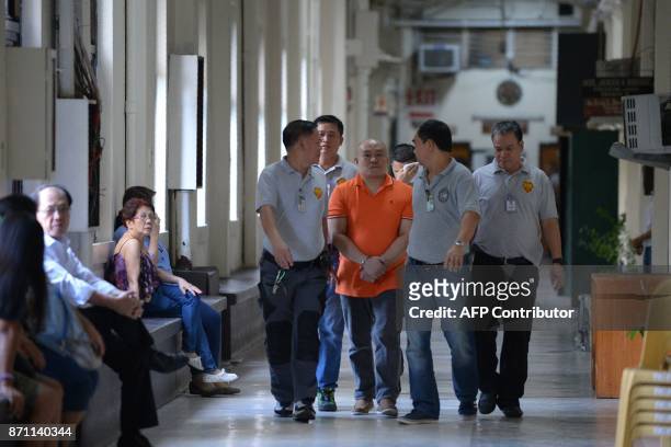 Philippine doctor Russell Salic is escorted by National Bureau of Investigation agents for a court hearing in Manila on November 7, 2017. A...