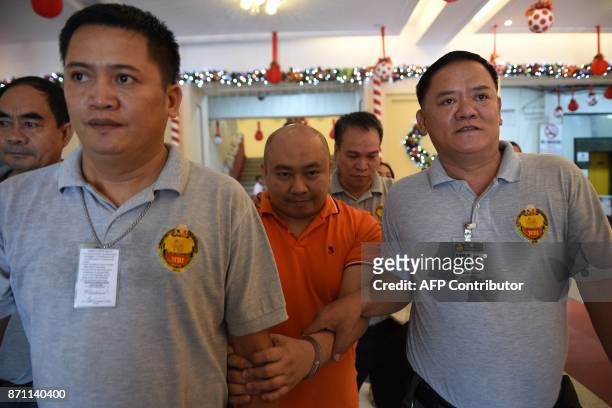 Philippine doctor Russell Salic is escorted by National Bureau of Investigation agents following a court hearing in Manila on November 7, 2017. A...