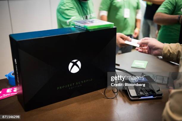 Customer, right, uses his credit card to purchase an Xbox One X game console ahead of its midnight release during the Microsoft Corp. Global launch...