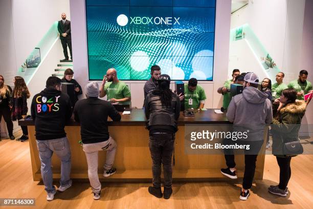 Customers wait at a counter to purchase the Xbox One X game consoles ahead of it's midnight release during the Microsoft Corp. Global launch event in...