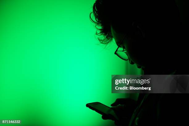 Customer uses his smartphone while waiting in line to purchase an Xbox One X game console during the Microsoft Corp. Global launch event in New York,...