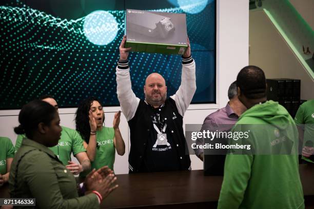 Aaron Greenberg, global manager for Xbox at Microsoft Corp., holds up an Xbox One X game console before presenting it to the first customer in the...