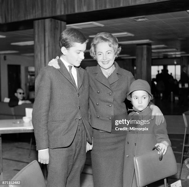 Olivia De Havilland at London Airport with her children Benjamin and Gisele waiting for a flight home to Paris, 15th April 1964.