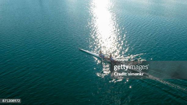 due atlete che sculling sul lago sotto il sole - sweep rowing foto e immagini stock