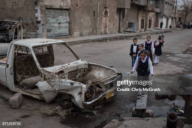 Children walk to school past destroyed cars in West Mosul on November 6, 2017 in Mosul, Iraq. Five months after Mosul, Iraq's second-largest city was...