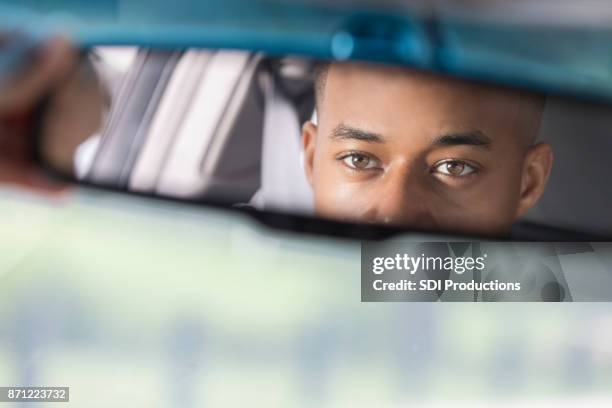 closeup of young man's reflection in rear view mirror - looking from rear of vehicle point of view stock pictures, royalty-free photos & images