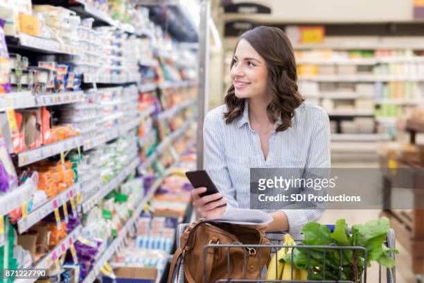 junge frau kauft in molkerei abschnitt der supermarkt - lady groceries phone stock-fotos und bilder