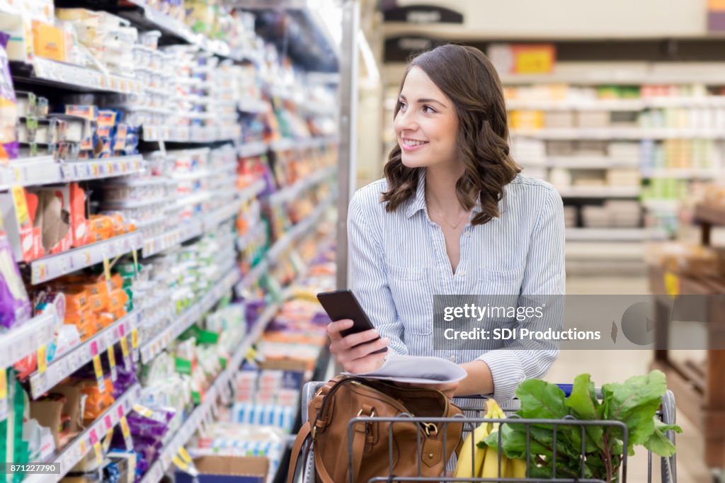 Young woman shops in dairy section of grocery store