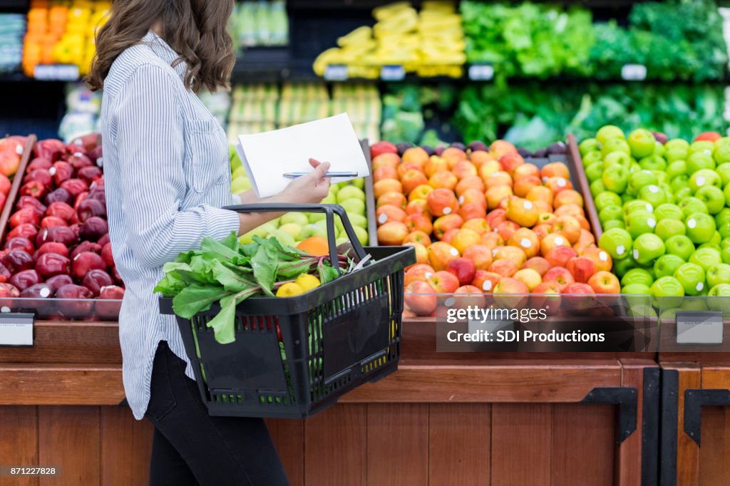Onherkenbaar vrouw winkels voor produceren in supermarkt