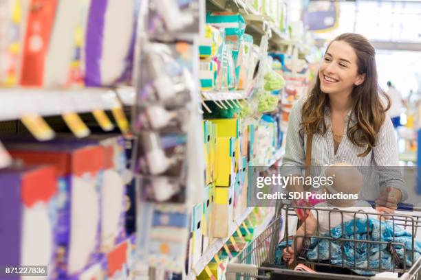 la giovane madre sfoglia la navata del bambino al supermercato - attrezzatura per neonato foto e immagini stock