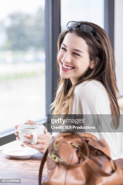 mujer joven alegre disfruta de café por una ventana - célula cultivada fotografías e imágenes de stock