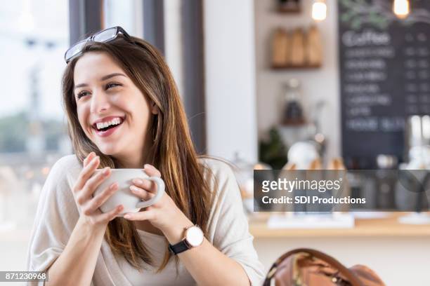 una joven se ríe durante la pausa café de cafetería - célula cultivada fotografías e imágenes de stock