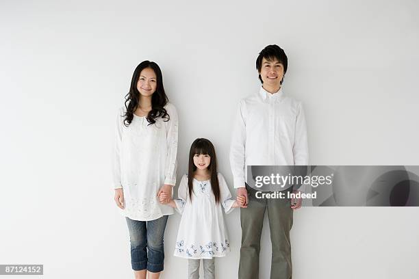 parents and daughter holding hands, portrait - couple sourire studio photos et images de collection