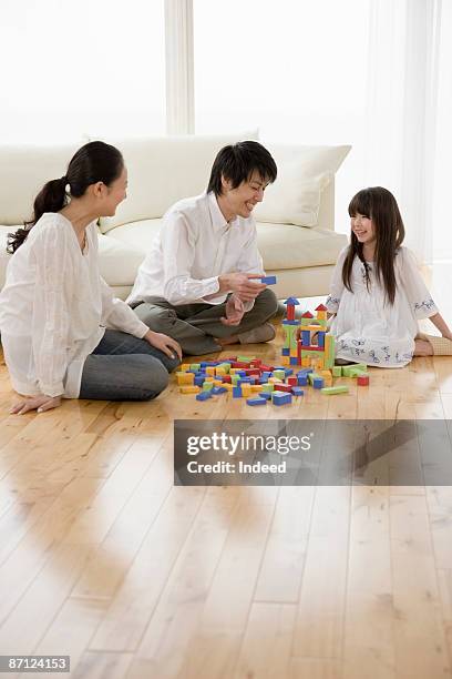 parents and daughter playing with blocks on floor - small child sitting on floor stockfoto's en -beelden