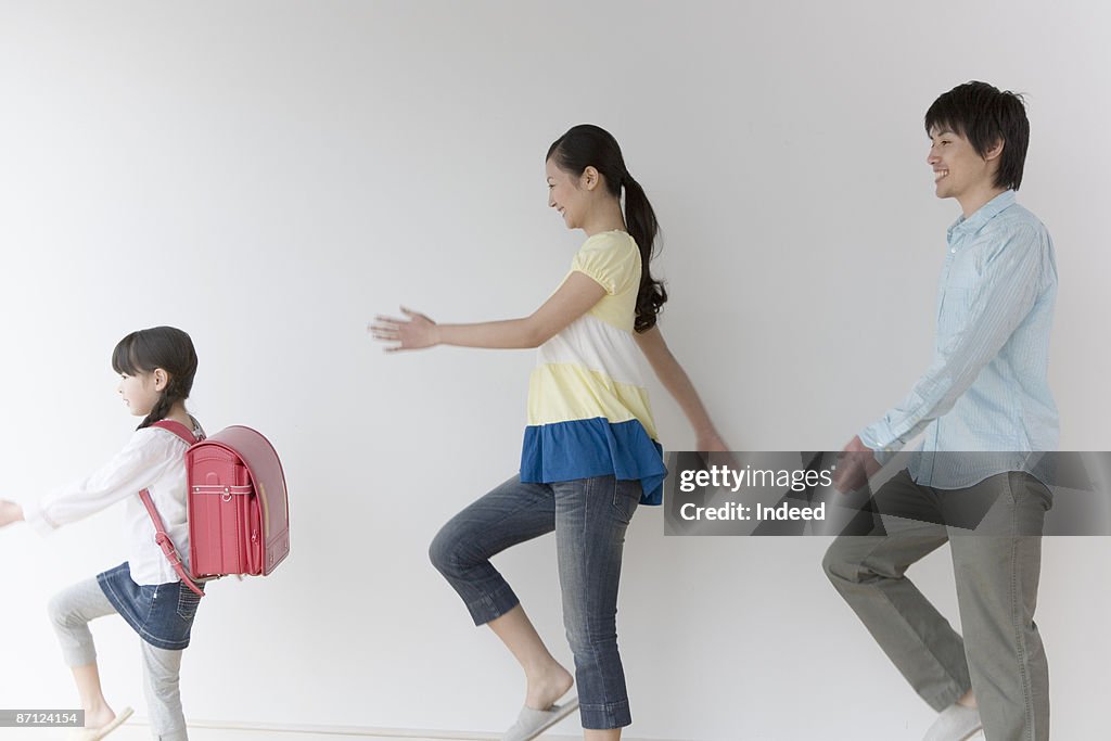 Parents and daughter marching, side view