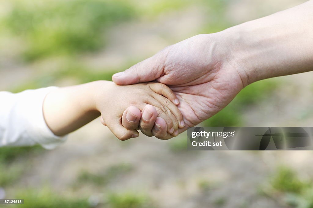 Baby boy and father holding hands,close up