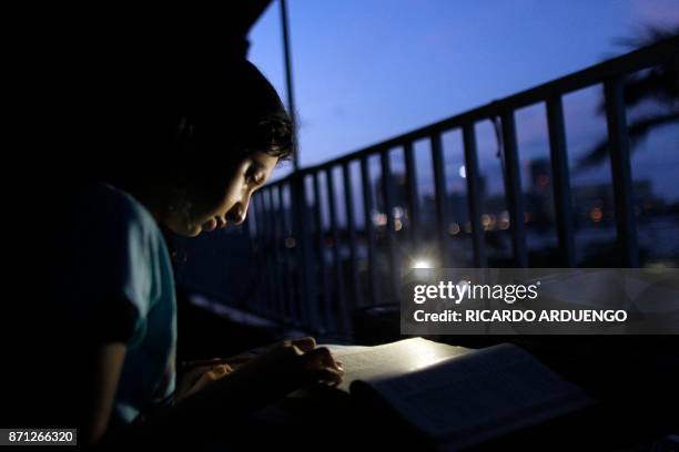 Alana Rivera, age 10, does her daily homework in her apartment balcony lit by a cell phone light in San Juan, Puerto Rico, November 6, 2017. The...