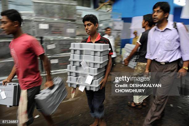 Election Commission workers carry Electronic Voting Machines to disbursement counters on the eve of the last phase of voting in Kolkata on May 12,...