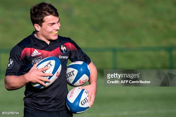French national rugby union team scrumhalf Antoine Dupont holds balls as he practices during a training session in Marcoussis, near Paris, on...