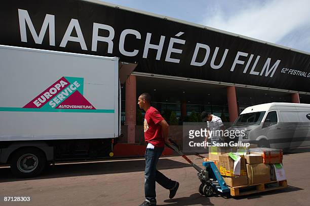 Worker pulls preparation supllies past the entrance to the Cannes festival Film Market one day prior to the opening of the Cannes International Film...