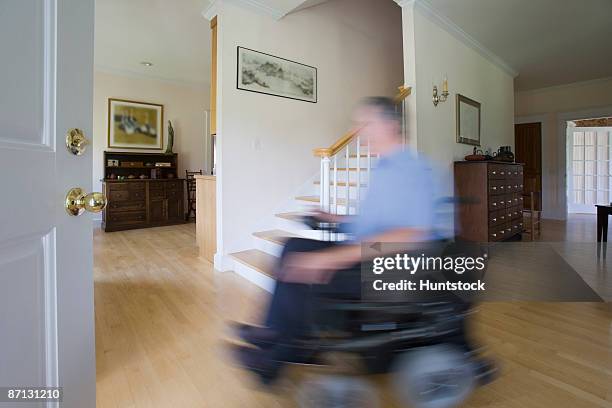 man with polio on electric wheelchair at home, blurred in motion - motorized wheelchair stock pictures, royalty-free photos & images