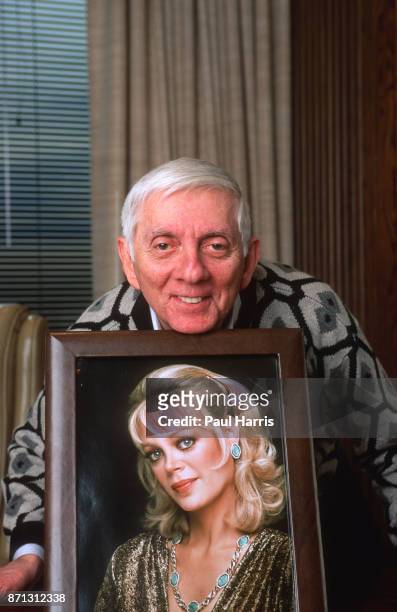 Aaron Spelling, television producer, famous for shows 90210 that his daughter starred in and Dynasty poses with a picture of his wife Candy Spelling...