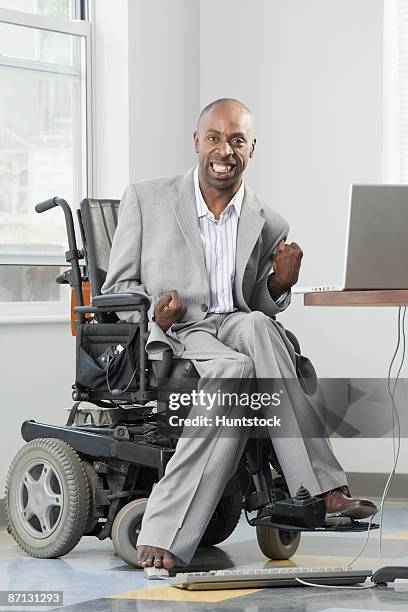 businessman with cerebral palsy working on a computer with his foot - man in wheelchair stock pictures, royalty-free photos & images