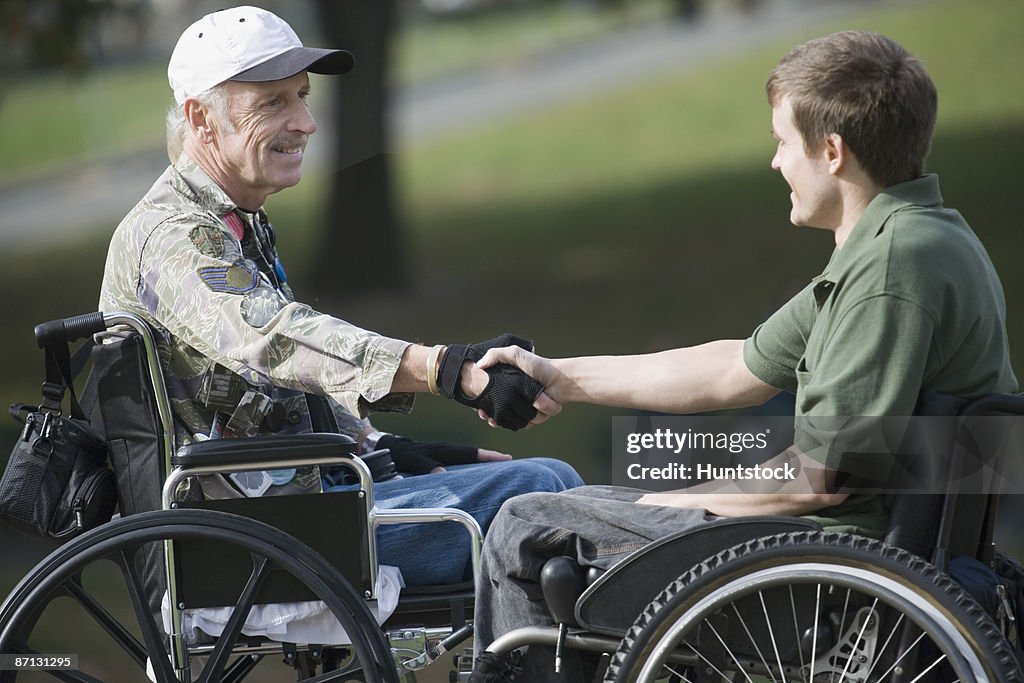 Side profile of a mature war veteran shaking hands with a young man