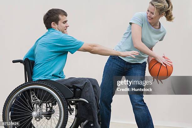 side profile of a young handicapped man playing basketball with a mid adult woman - man in wheelchair stock pictures, royalty-free photos & images