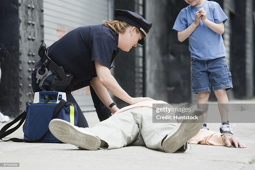 Woman police officer administering first aid to a senior man