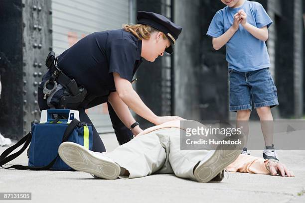 woman police officer administering first aid to a senior man - police rescue stock pictures, royalty-free photos & images