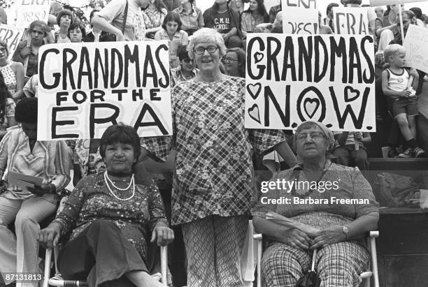 Older women gather at a demonstration in support of passage of the Equal Rights Amendment, Pittsburgh PA, 1976. Three foreground women's signs read...